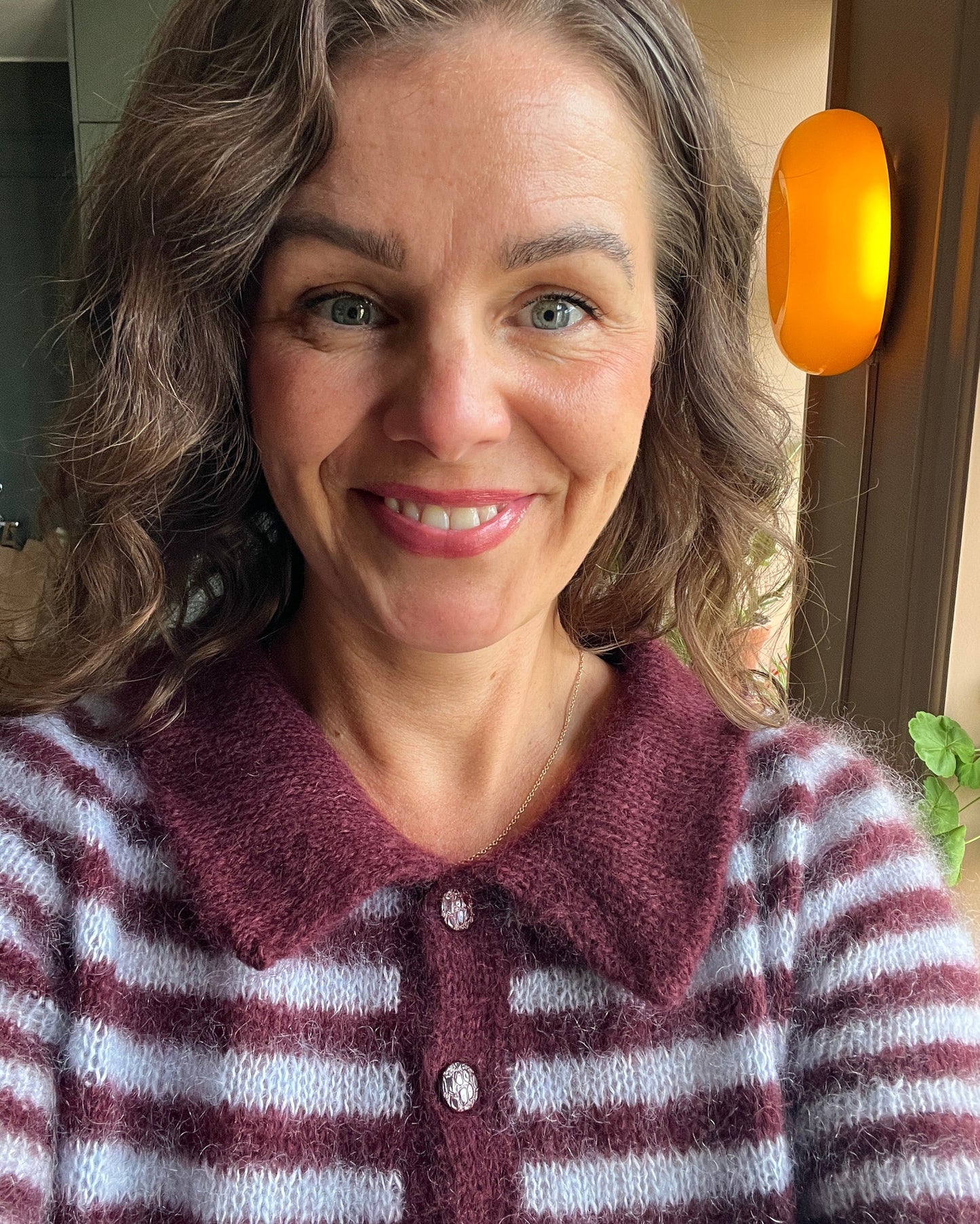 Woman wearing fuzzy maroon and white striped knit polo