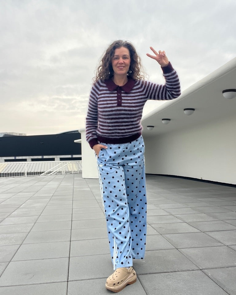 Woman styling maroon and white striped polo with wide-leg pants