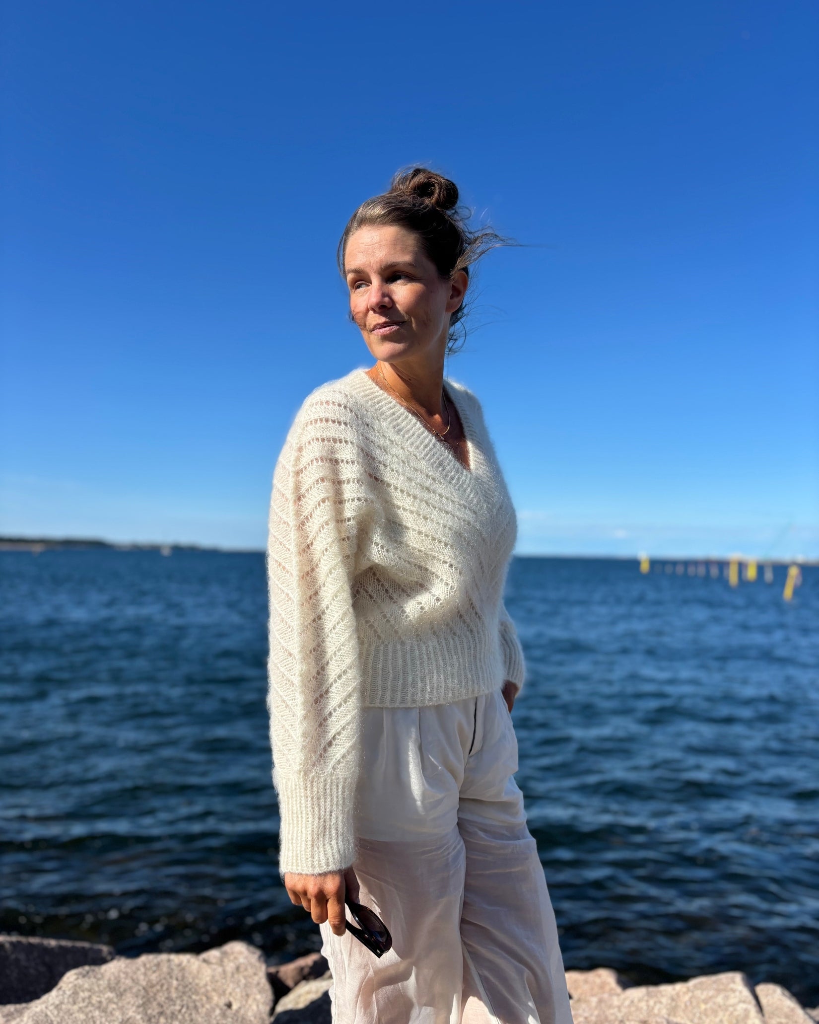 Woman wearing cream cropped sweater with diagonal lace pattern and wide leg pants