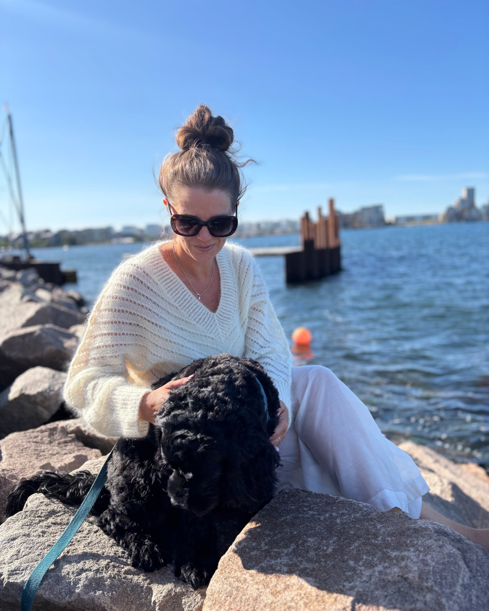 Cream cropped knit sweater with lace pattern worn by woman near water