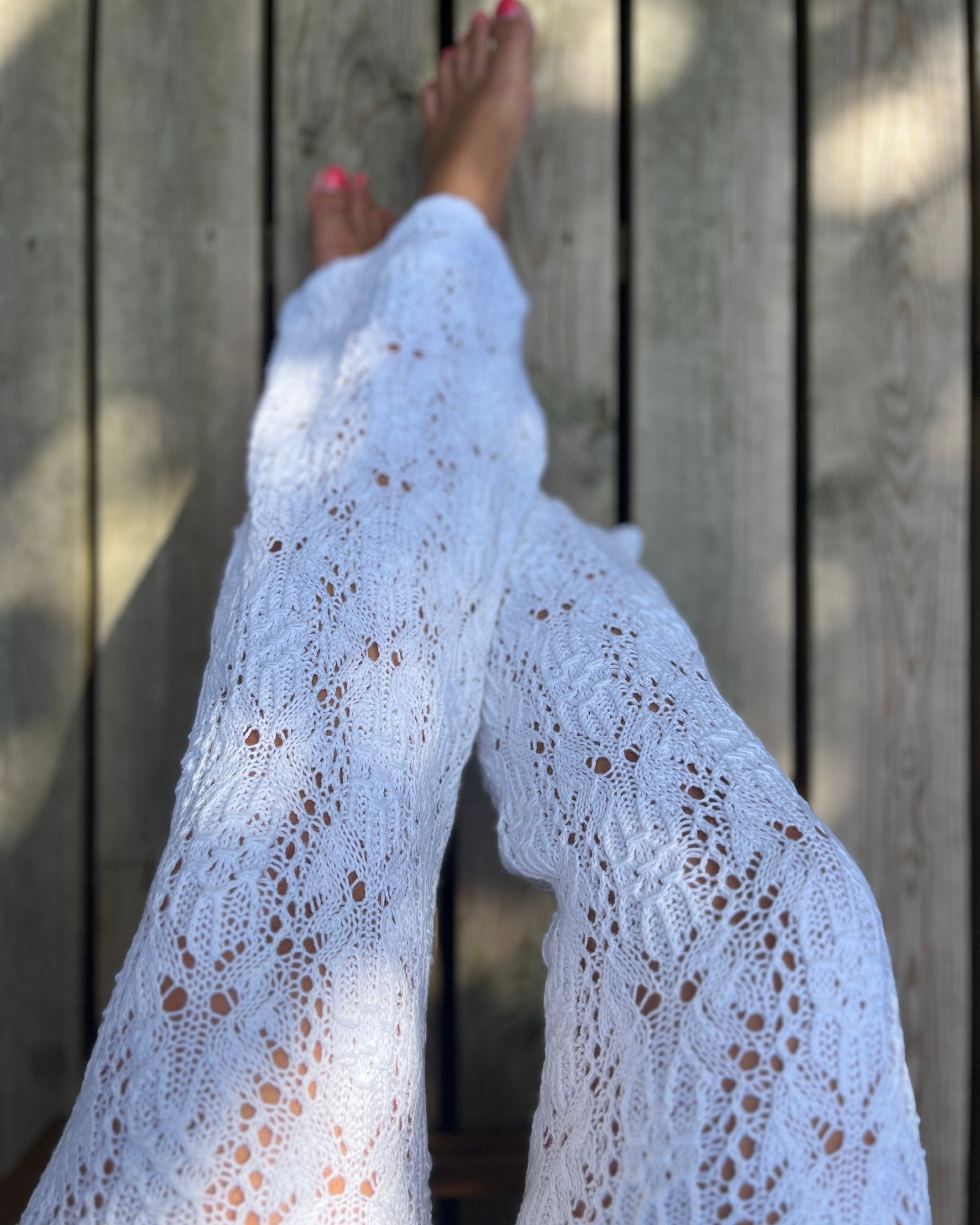 White lace and smock knit pants worn by a model, shown from a top-down perspective against a wooden plank background.